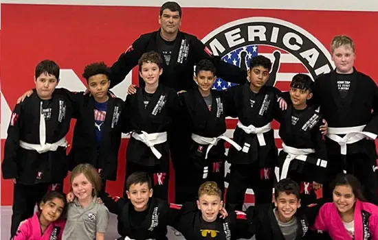 Kids in Brazilian Jiu Jitsu class standing together, celebrating their training progress