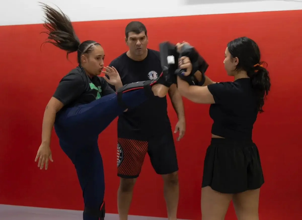 Young martial arts student breaking board with instructor