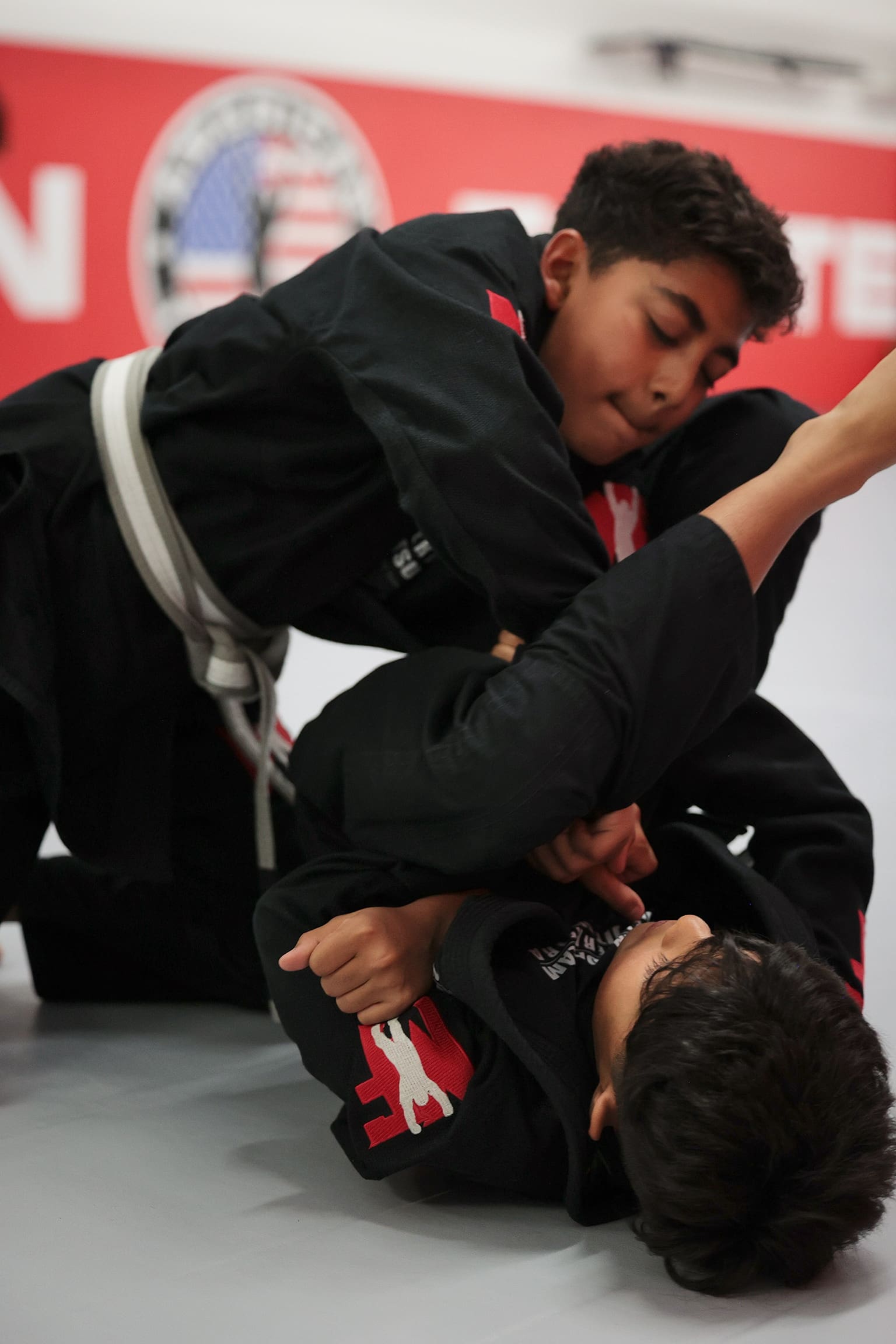 Martial arts kids classes train jiu-jitsu through programs like Royce Gracie bullyproof and Gracie Barra, where assistant instructors and training partners help develop goal setting, core strength, discipline, confidence, respect, and fundamental awareness from the white belt level while making new friends.