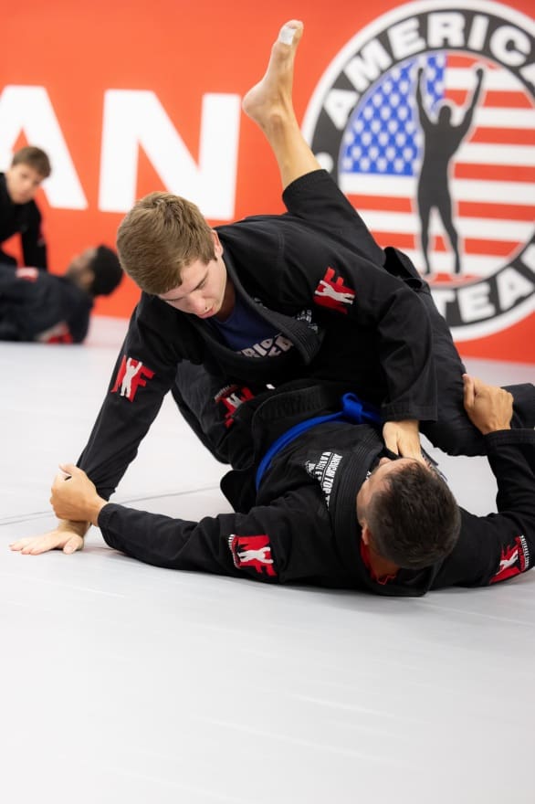 Teens performing a Jiu-Jitsu move on the mats